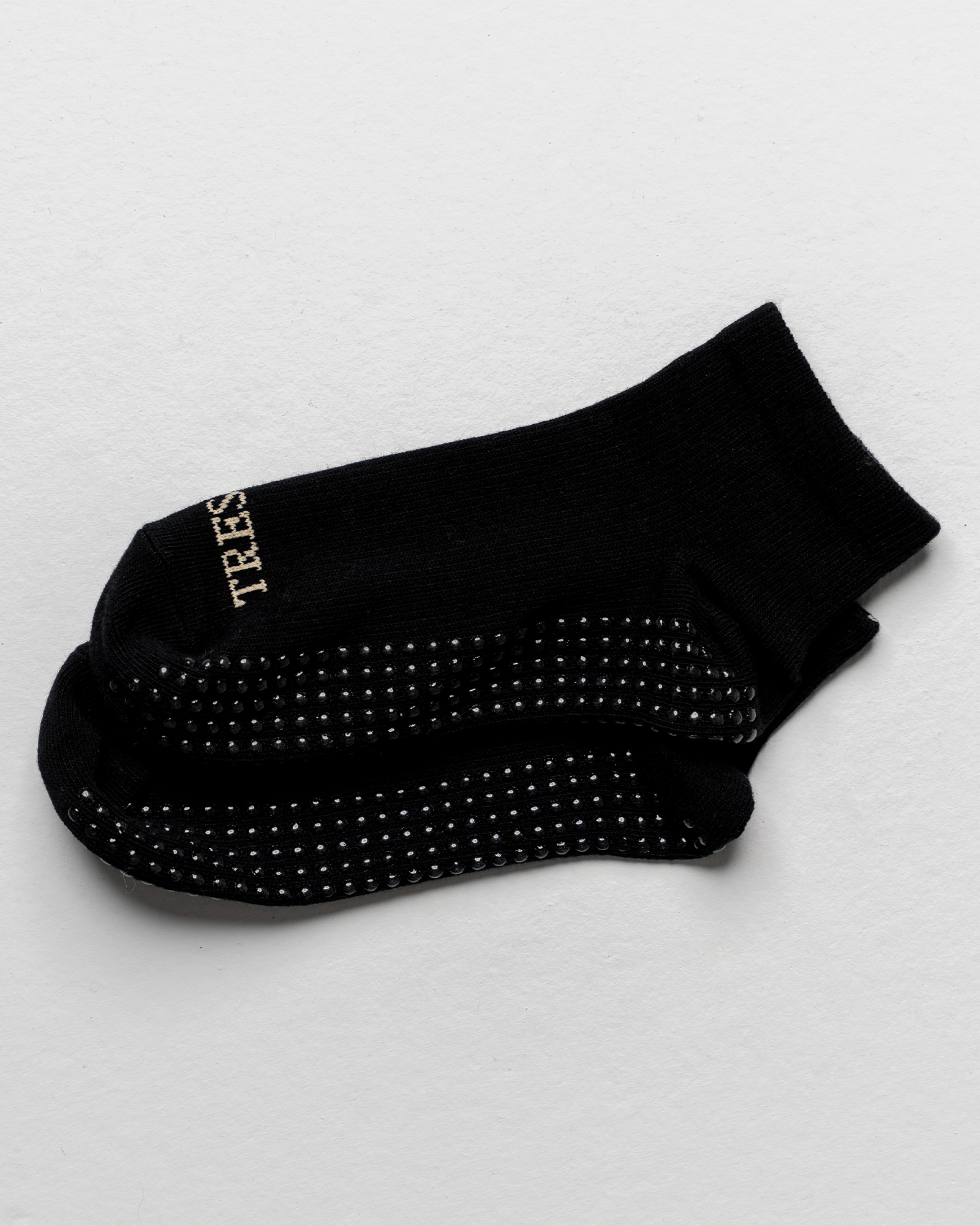 Black sock with textured sole on a light gray background