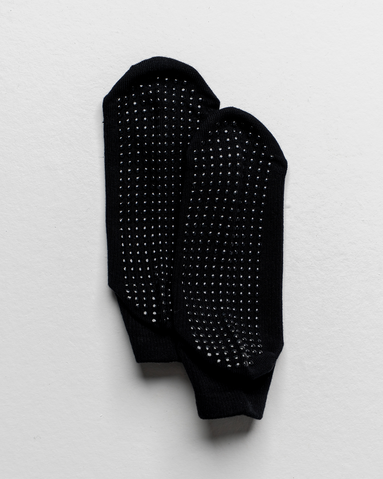 Black socks with textured sole on a light gray background