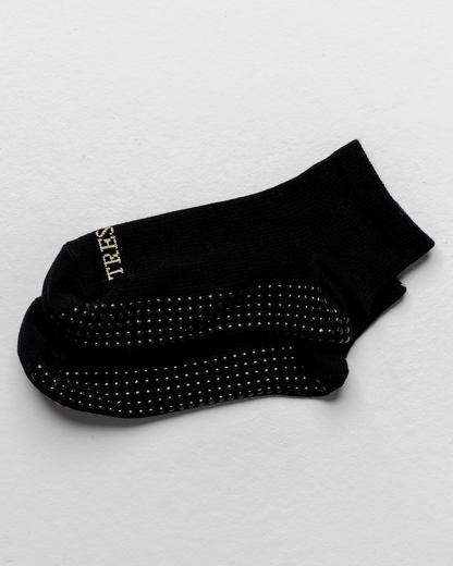 Black sock with textured sole on a light gray background