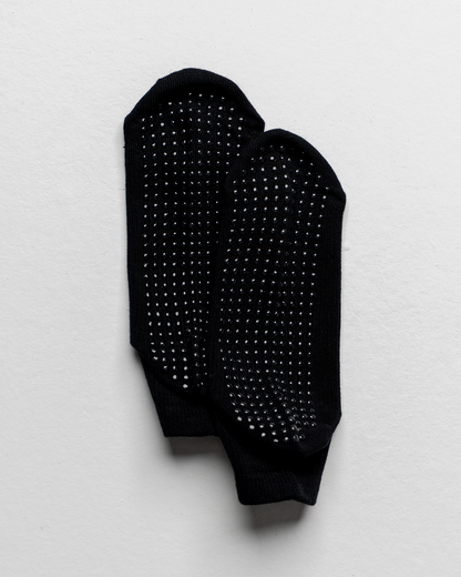 Black socks with textured sole on a light gray background